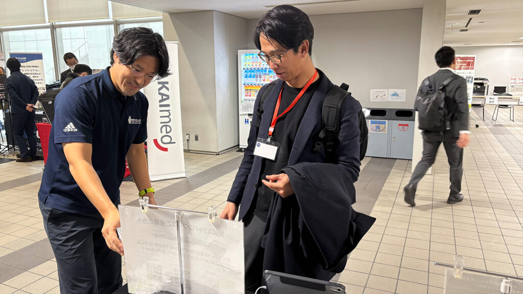 NSCAジャパンブースで話をする2人の男性