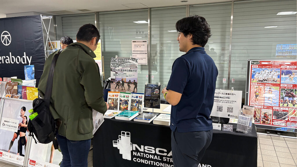NSCAジャパンブースで話をする2人の男性