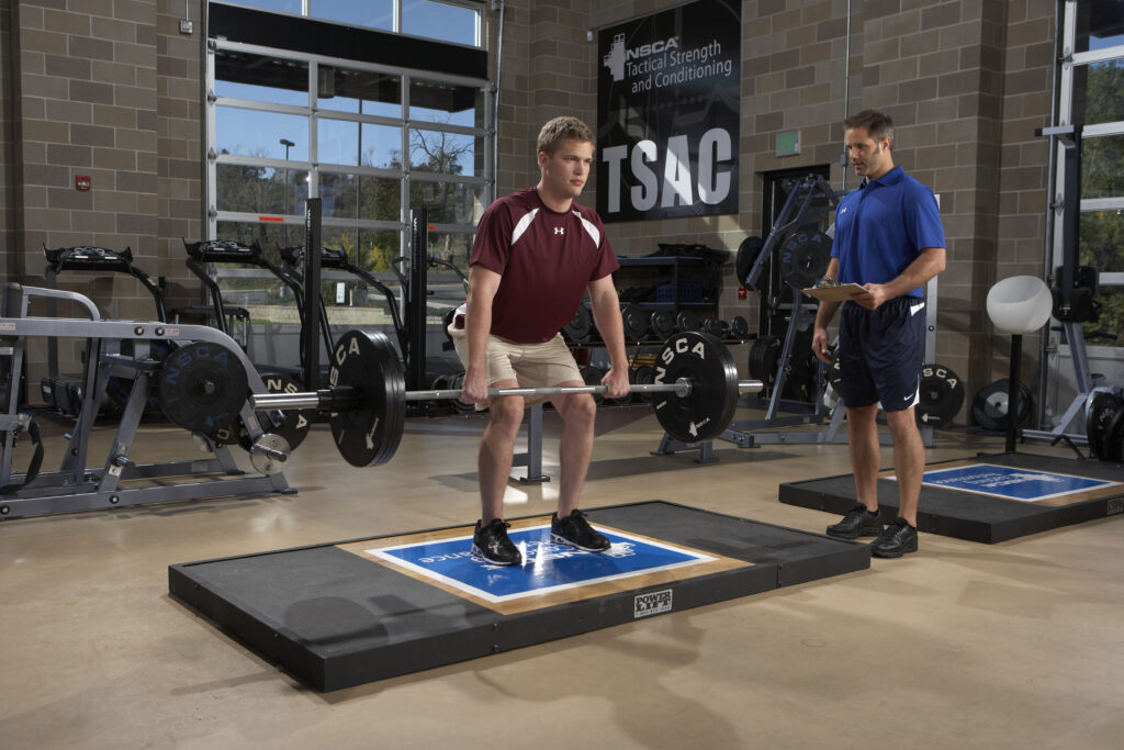 トレーナーとバーベルでトレーニングをしている人