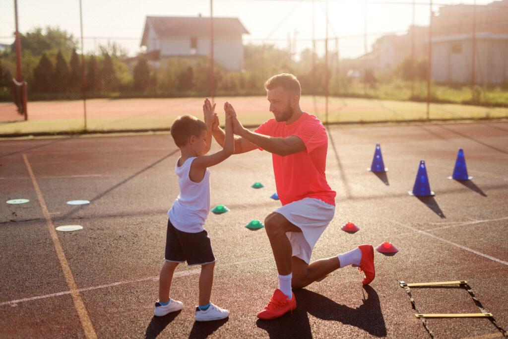 運動場でハイタッチをする父親と息子
